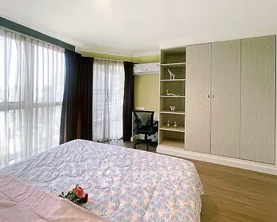 Spacious bedroom with large windows and built-in wardrobe in modern apartment