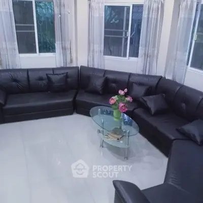 Spacious living room with modern black leather sectional sofa and glass coffee table.