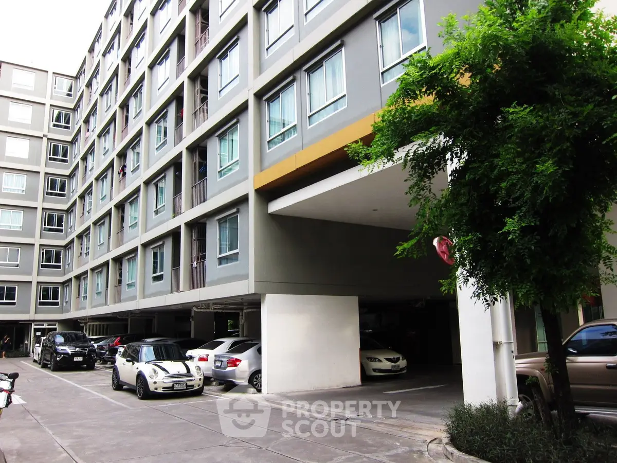 Modern apartment building with parking area and lush greenery