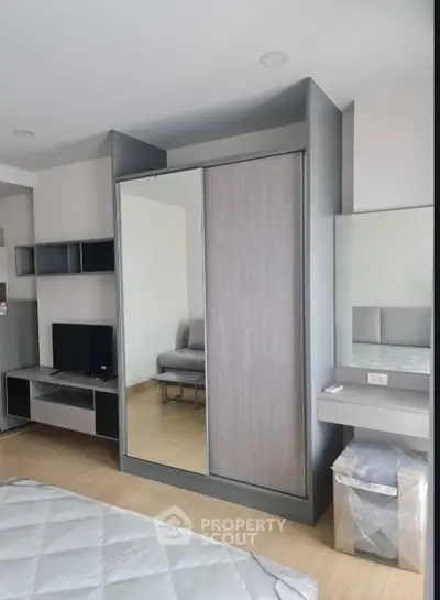 Modern bedroom with sleek wardrobe and entertainment unit in stylish apartment.