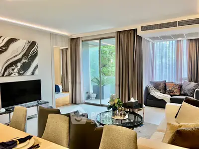Luxurious living room with modern decor and large windows opening to a lush balcony view.