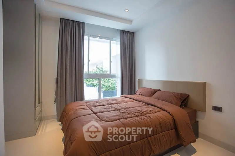 Cozy bedroom with modern decor and large window for natural light.