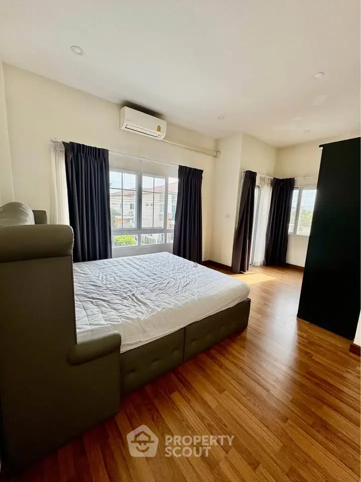 Spacious bedroom with large windows and wooden flooring, perfect for natural light lovers.