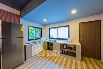 Modern kitchen with sleek design, featuring stainless steel fridge and ample counter space.
