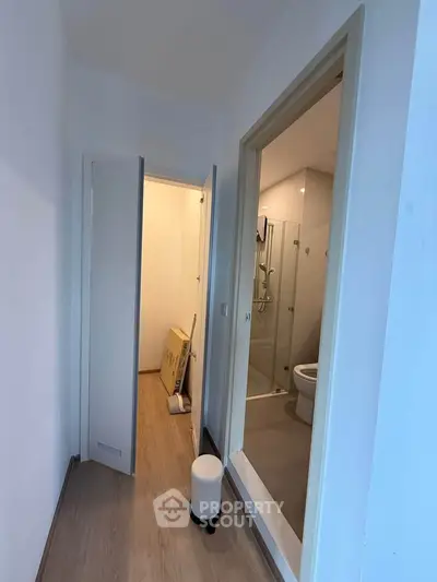 Compact hallway leading to a modern bathroom with glass shower enclosure.