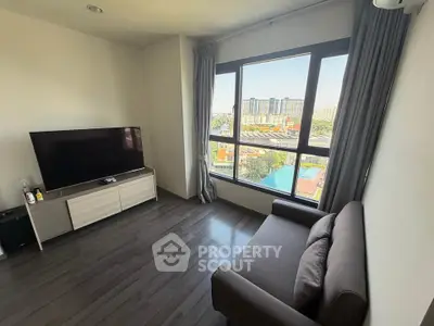 Modern living room with large window and city view, featuring sleek furniture and natural light.