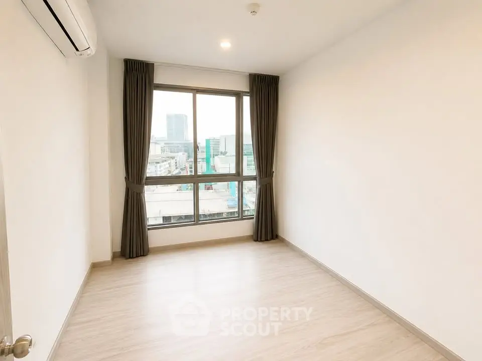 Spacious empty room with large window offering city view, perfect for customization.