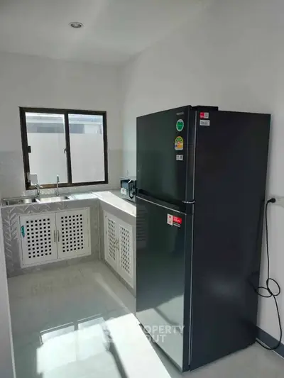 Modern kitchen with sleek black fridge and ample natural light