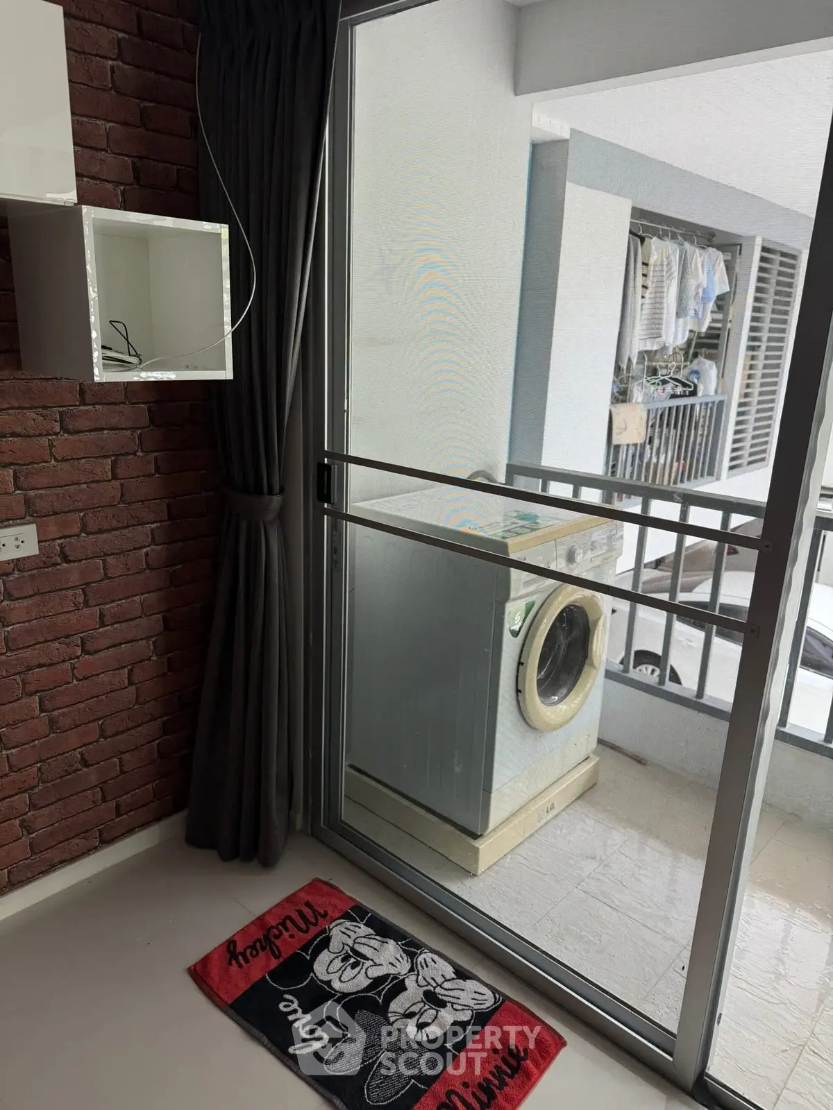 Cozy apartment with balcony featuring washing machine and brick accent wall.