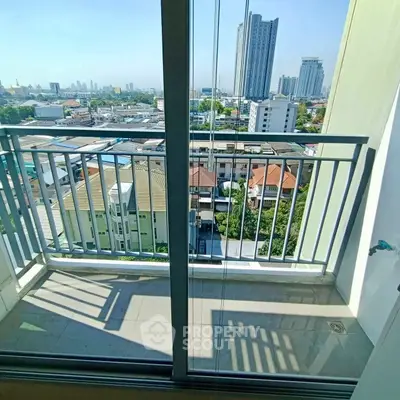 Stunning city view from a modern apartment balcony with glass doors.