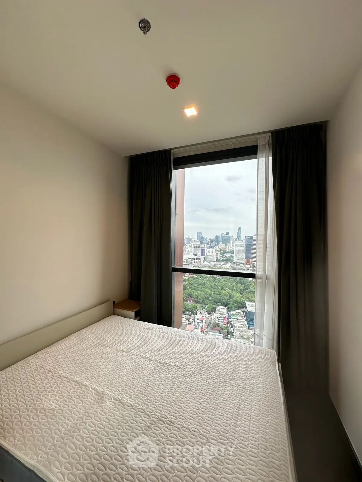 Modern bedroom with stunning city view from large window, featuring a comfortable bed and minimalist decor.
