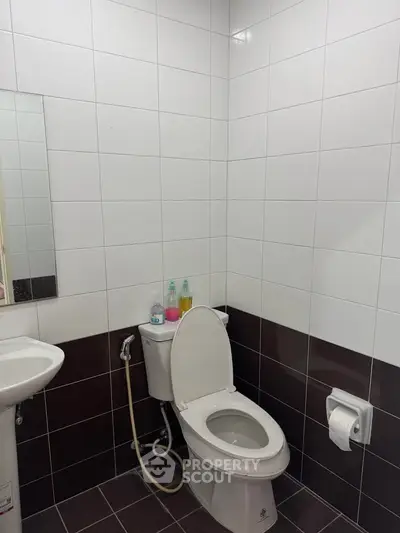 Modern bathroom with white tiles and essential fixtures in a real estate property.