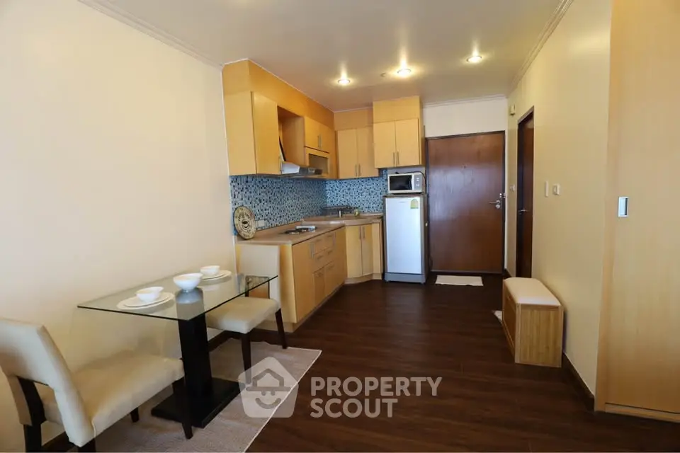 Modern kitchen and dining area with wooden cabinets and glass table in cozy apartment.