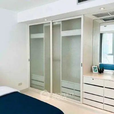 Modern bedroom with sliding closet doors and sleek dresser in a bright, minimalist design.