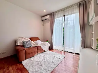 Cozy living room with plush sofa, wooden flooring, and large window for natural light.