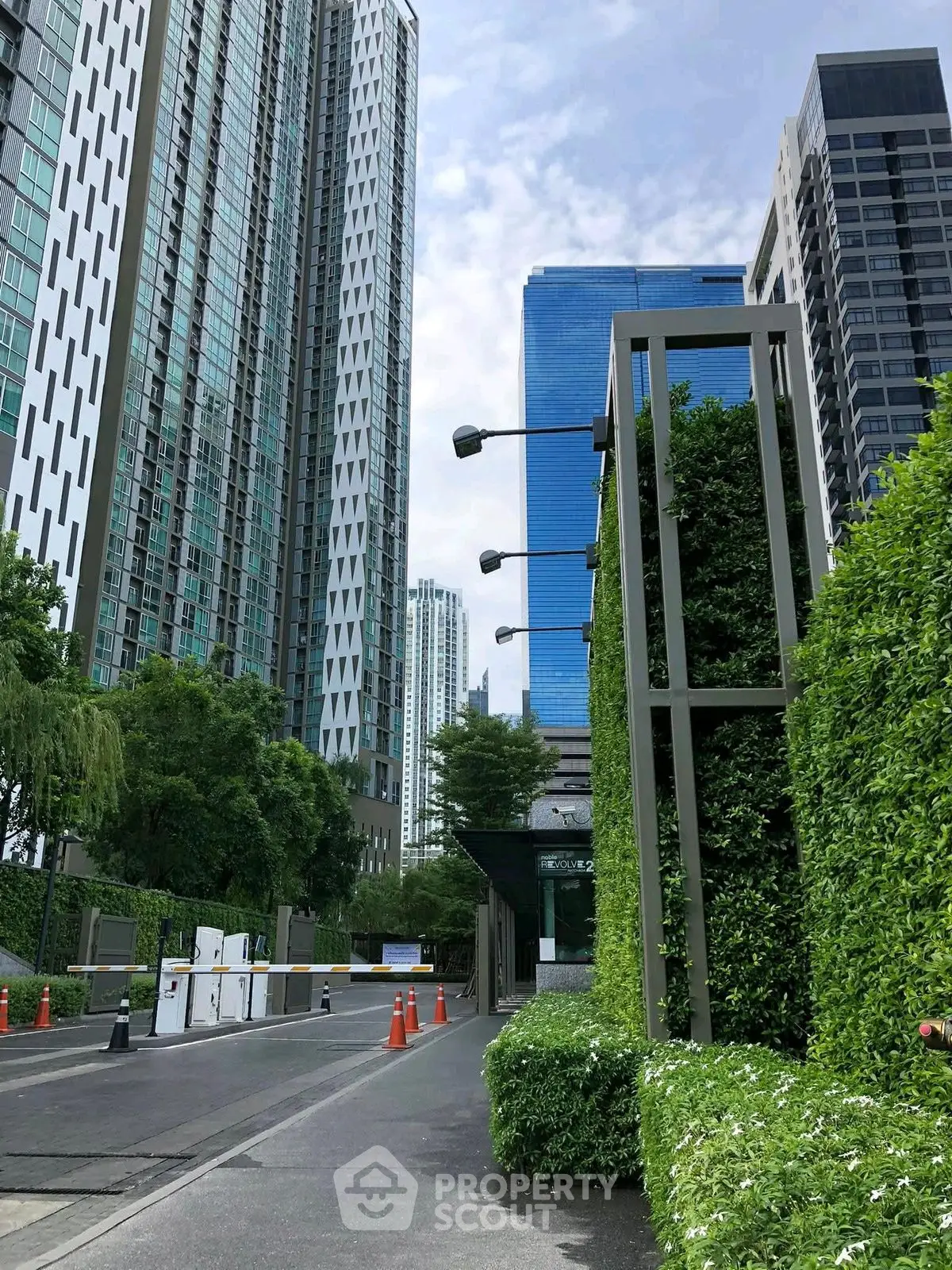 Modern high-rise buildings with lush greenery and secure entrance in urban setting.