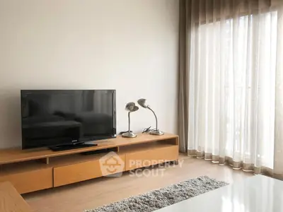 Modern living room with sleek TV stand and floor-to-ceiling curtains, perfect for cozy relaxation.