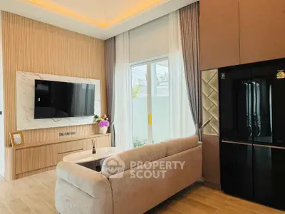 Modern living room with elegant decor and large TV, featuring a cozy sofa and stylish lighting.