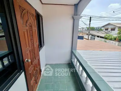 Charming small balcony with green tiles and wooden door, offering a cozy outdoor space.