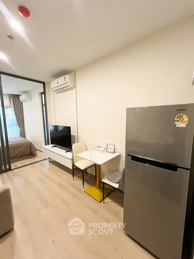 Modern apartment interior with open layout, featuring a cozy living area and sleek kitchen appliances.