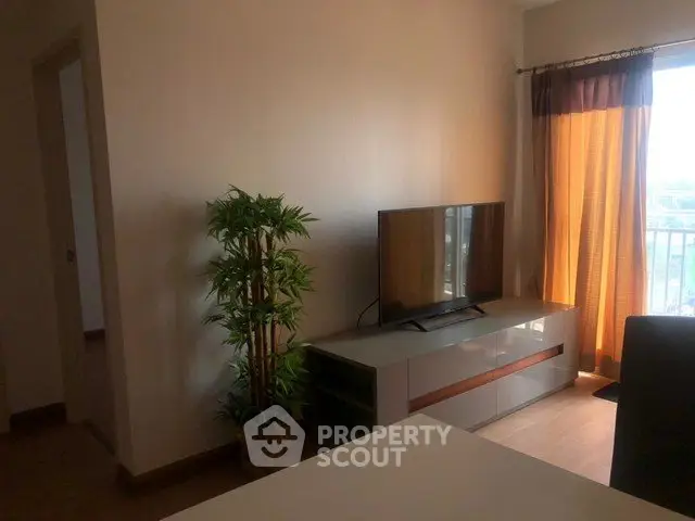 Cozy living room with TV and natural light from balcony