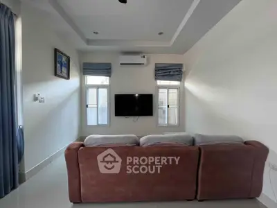 Cozy living room with modern sofa and wall-mounted TV, perfect for relaxation.