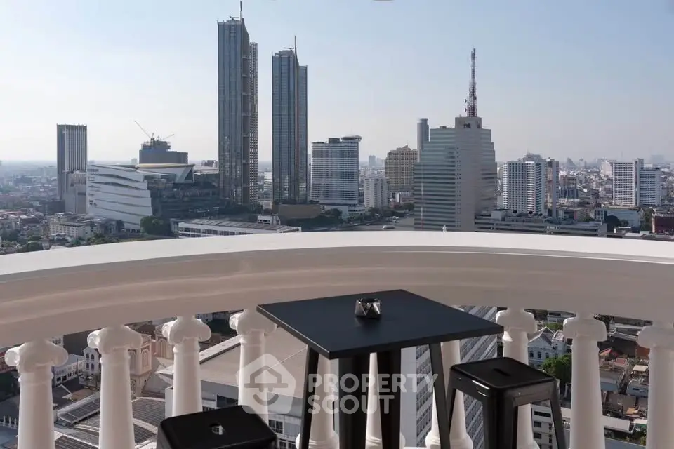 Stunning cityscape view from a high-rise balcony with modern seating, perfect for urban living.