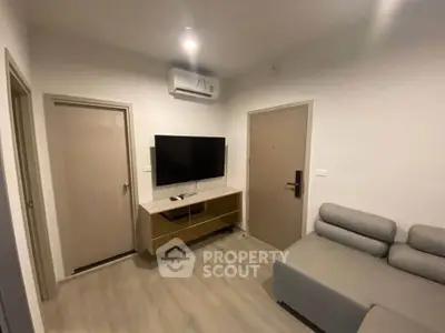 Modern living room with sleek furniture and wall-mounted TV in a cozy apartment.