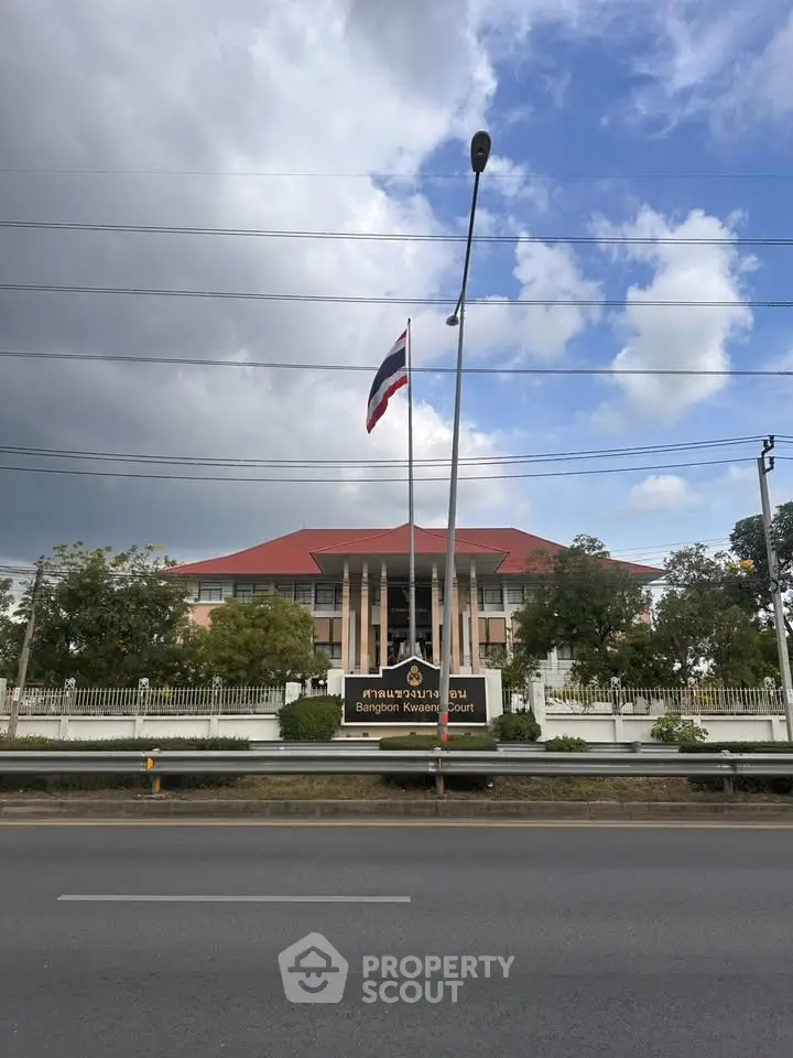 Impressive government building with red roof and flag, showcasing grand architecture and lush surroundings.