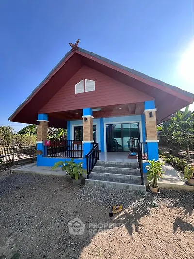 Charming single-story house with vibrant blue accents and inviting front porch