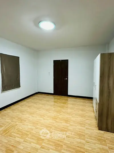 Spacious empty room with wooden flooring and modern wardrobe, ideal for customization.