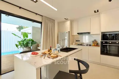 Modern kitchen with open layout and poolside view, featuring sleek appliances and stylish decor.