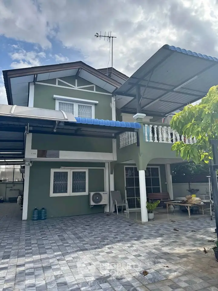 Charming two-story green house with spacious tiled driveway and covered patio, perfect for family living.