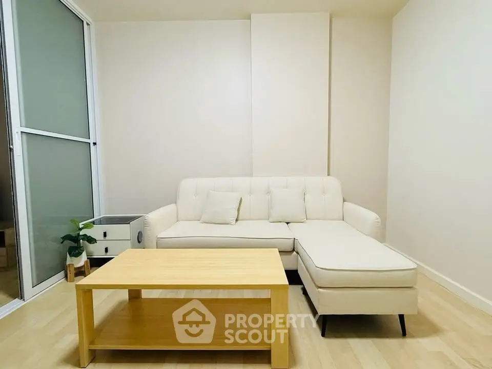 Modern living room with cream sofa and wooden coffee table in a bright, minimalist setting.