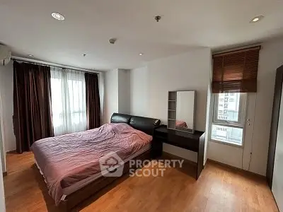 Spacious bedroom with modern furnishings and large windows for natural light.