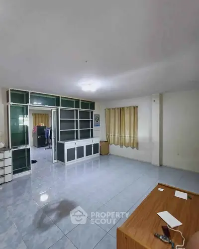 Spacious living room with tiled flooring and large windows in a modern apartment.