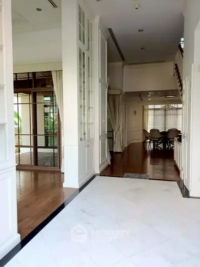 Spacious open-plan living area with elegant wooden flooring and large windows.