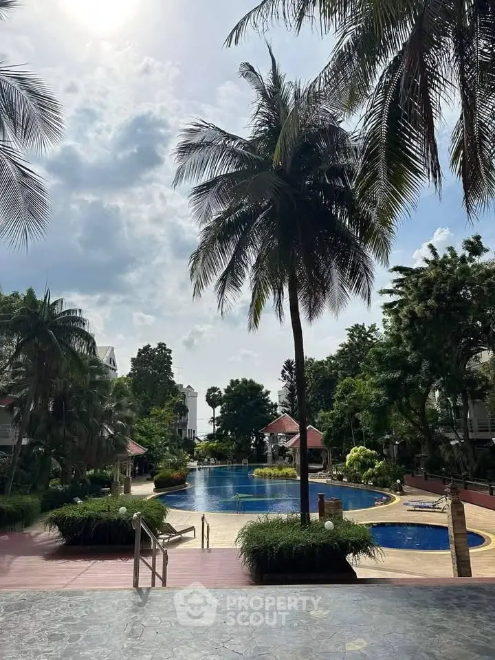 Luxurious poolside view with palm trees and serene surroundings in a tropical setting.