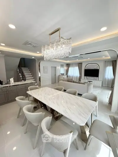 Luxurious open-plan living and dining area with elegant chandelier and marble table