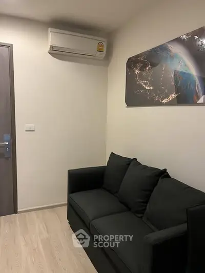 Cozy living room with modern sofa and wall art, featuring air conditioning.