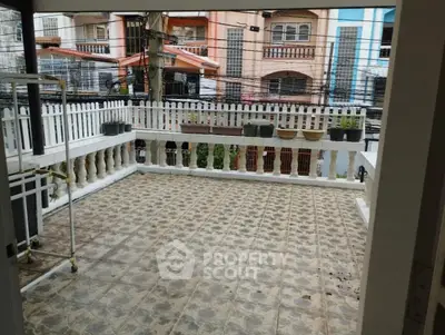 Spacious tiled balcony with white railing and city view, perfect for outdoor relaxation.