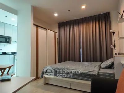 Modern bedroom with cozy bed and adjacent kitchen in stylish apartment