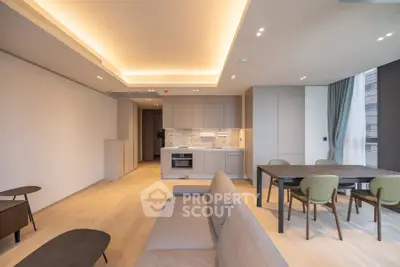 Modern open-plan living room with sleek kitchen and dining area, featuring elegant lighting and contemporary furniture.