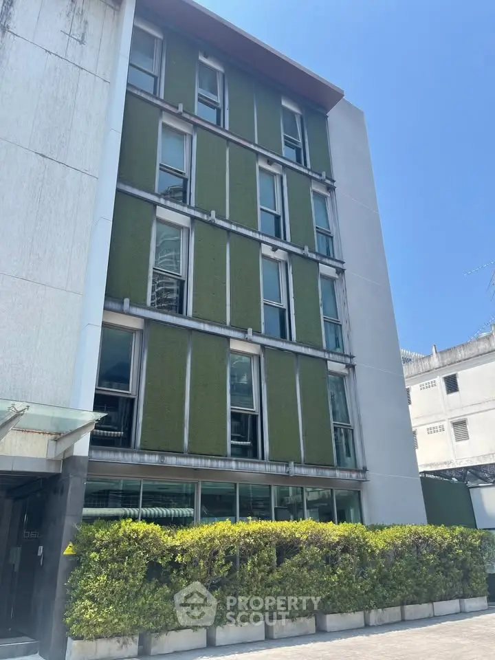 Modern building exterior with green facade and lush landscaping