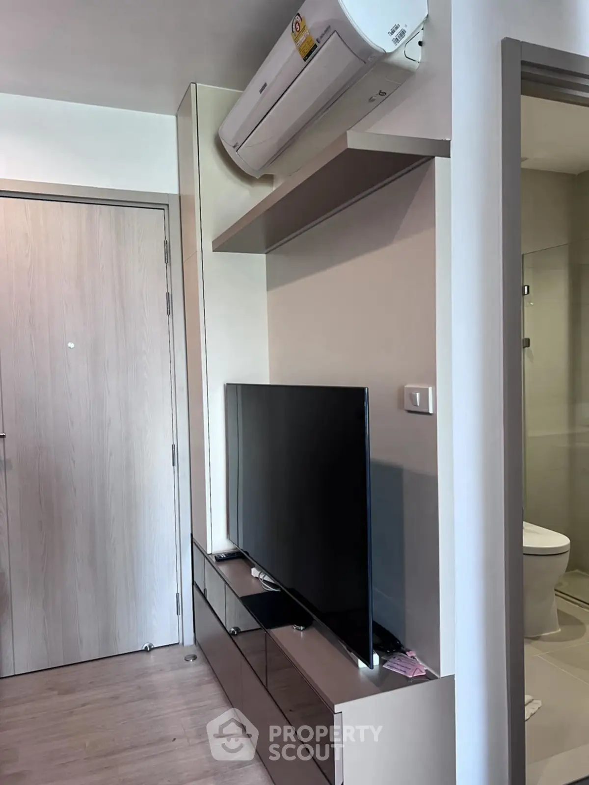 Modern apartment interior with sleek TV setup and air conditioning unit.
