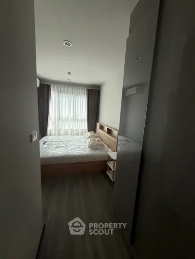 Cozy bedroom with modern furnishings and natural light through large window.