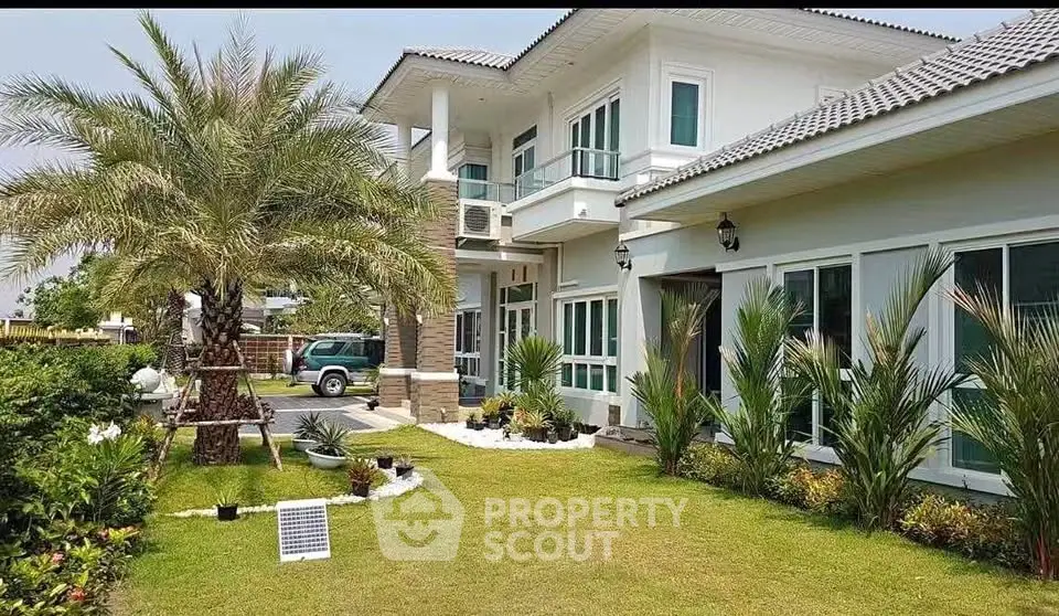 Luxurious modern house with lush garden and palm trees, showcasing elegant architecture and spacious outdoor area.