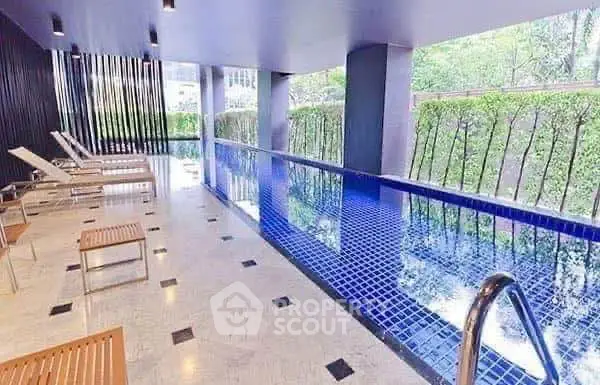 Luxurious indoor pool area with modern design and lush greenery view.