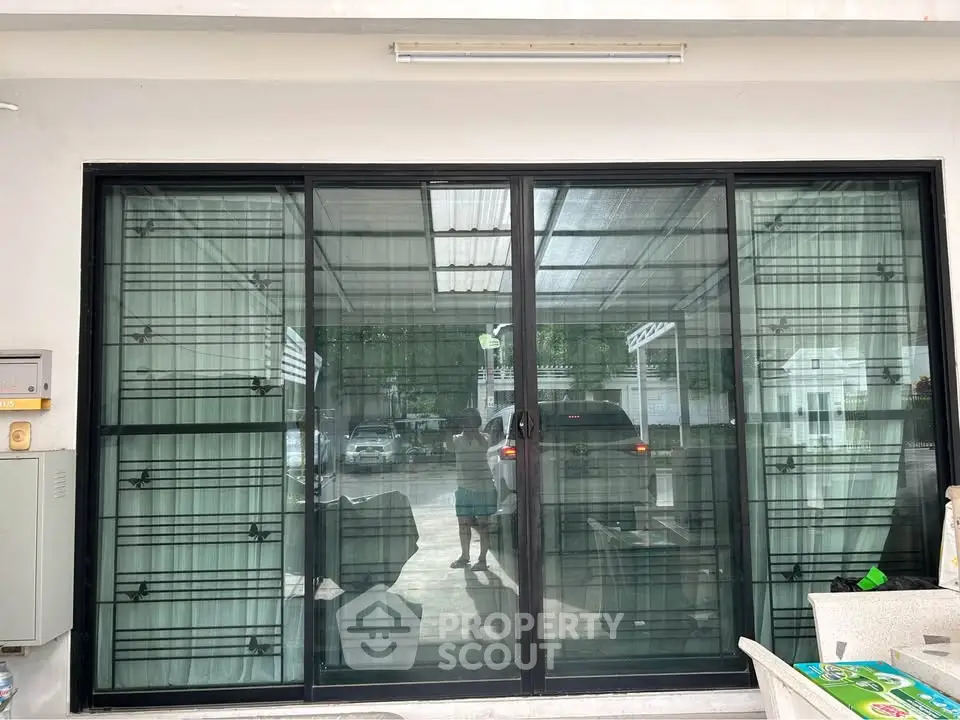 Modern glass sliding doors leading to a covered outdoor area with parking space.