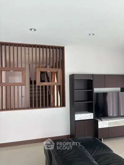 Modern living room with stylish wooden partition and sleek entertainment unit.